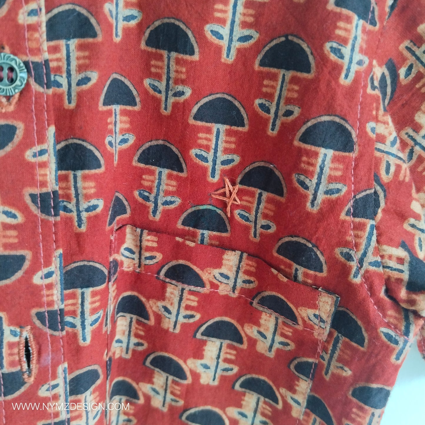 Close-up of star hand embroidery near pocket on Ajrakh brick red cotton kids shirt – handcrafted Indian handblock print design