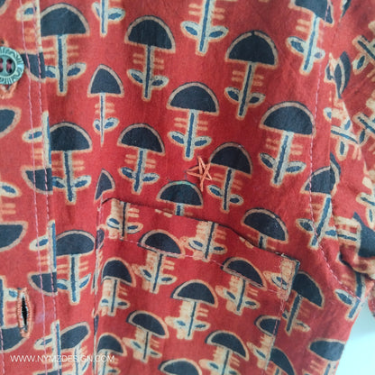 Close-up of star hand embroidery near pocket on Ajrakh brick red cotton kids shirt – handcrafted Indian handblock print design